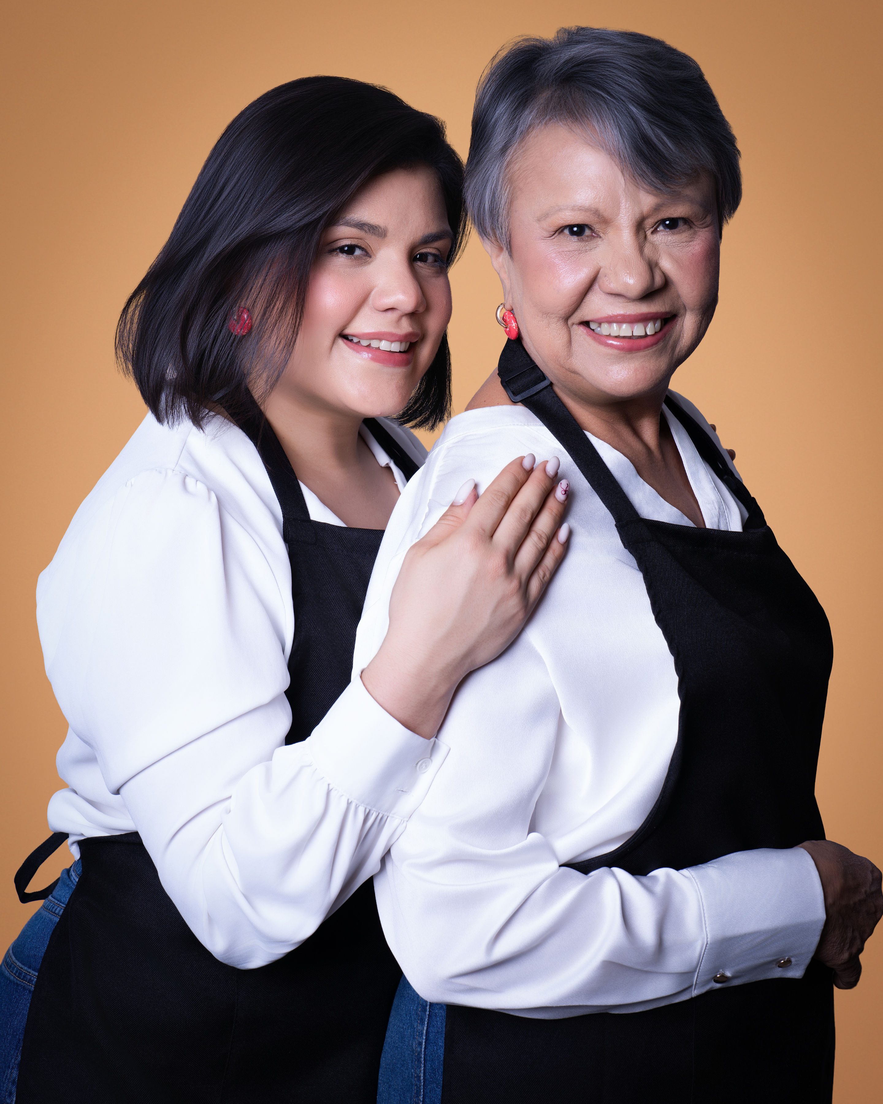 Madre e hija, reposteras detrás de Rica Tentación, sonriendo abrazadas en sesión de marca